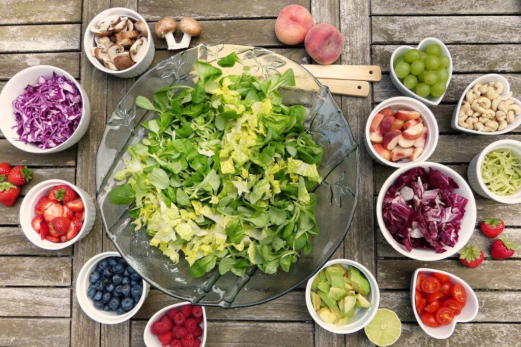 salade verte dans un saladier et petits bols avec des ingrédients pour faire une salade composée
